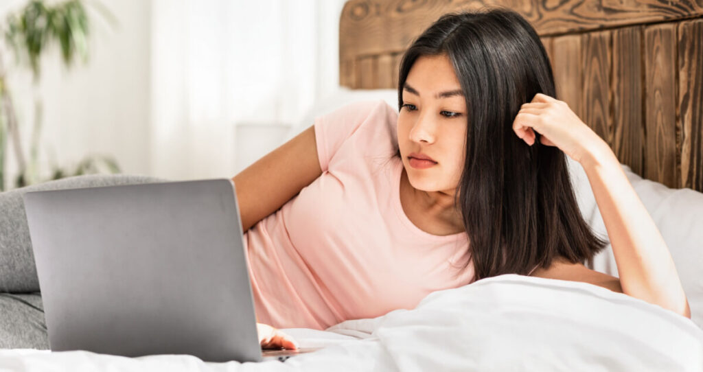 Girl lying in bed an using her laptop
