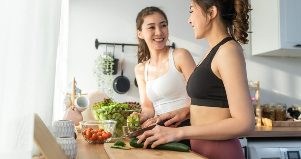 Two smiling women making a meal together in the kitchen