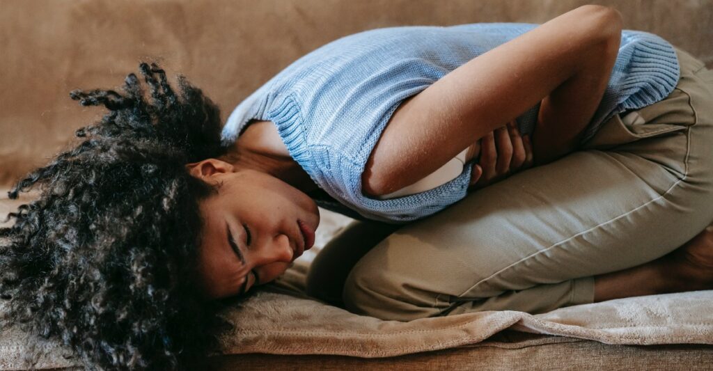 Woman lying in pain holding her belly