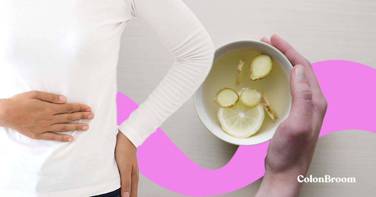 A woman in a white shirt standing with a hand on her belly. In the background we see a healthy tea