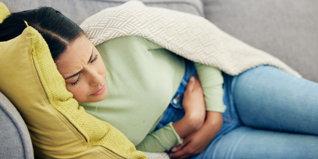 Woman with a bloated belly sleeping on the sofa in pain