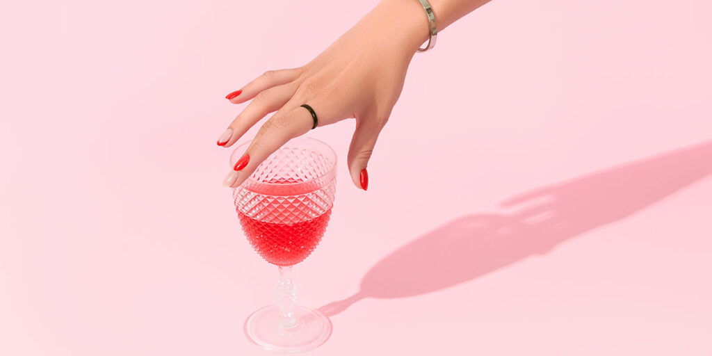 ColonBroom's pink strawberry cocktail and hand reaching to it