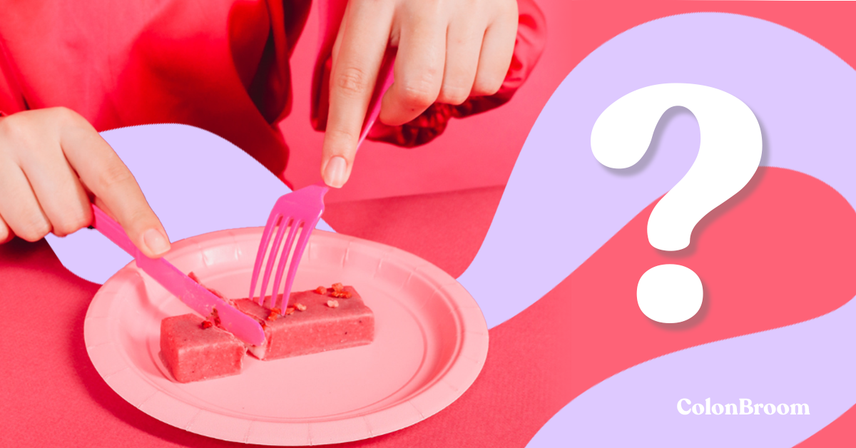 There is a bright pink plate with a pink protein bar on it, and a fork and knife are used to cut it.