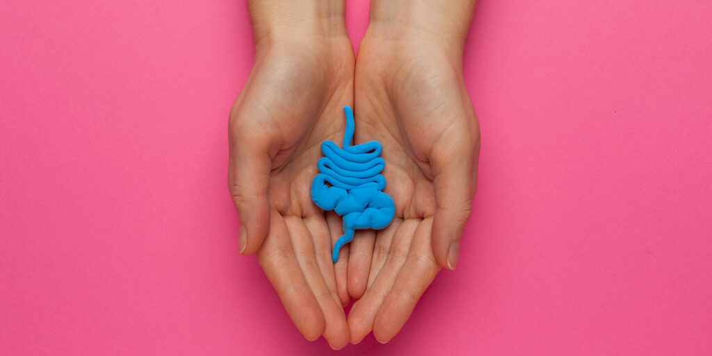 An image of hands holding a stylized gut in blue on a hot pink background.