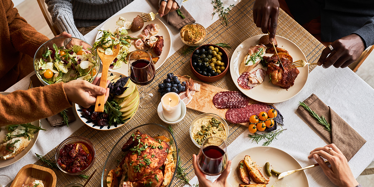 People are helping themselves to a variety of foods at a big thanksgiving table